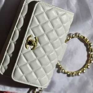 Off white Chanel bag with a gold and pearl handle.  With a shoulder strap